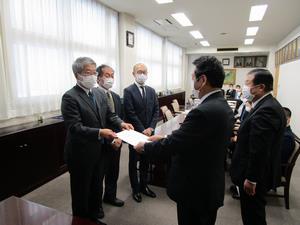 検証者から議長へ報告書提出の写真