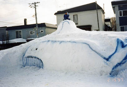 堆積された雪山で作られたクジラの雪像の写真