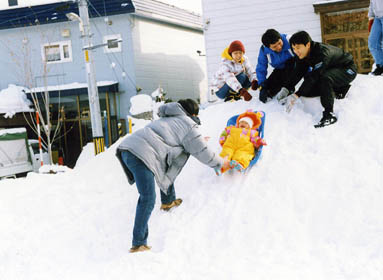 堆積された雪山でそり滑りをしている写真